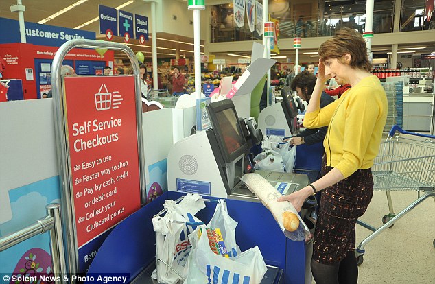 A shopper holds their head and looks confused as she tries to scan a baguette through a self-service till